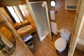 Un baño de madera pequeño y funcional con lavamanos, inodoro y ducha.