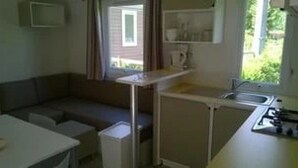 Una cocina compacta con estufa integrada, una superficie de trabajo pequeña y un ventanal.