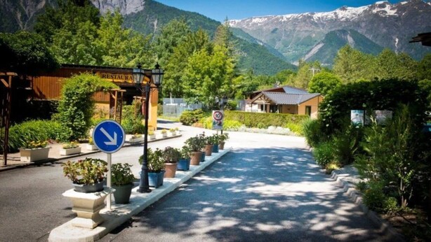 Un restaurante con vista a la montaña, una señal direccional azul y un cartel de prohibido estacionar.