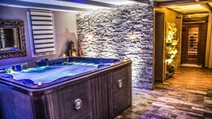 Un área de spa con hidromasaje, pared de piedra y suelo de madera.