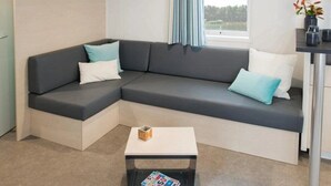 Una sala de estar moderna con un sofá seccional, una pequeña mesa de centro y vistas al exterior a través de una ventana.