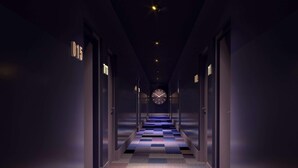 Een hotelgang met een geruit tapijt, deuren aan beide kanten en een klok aan de muur.