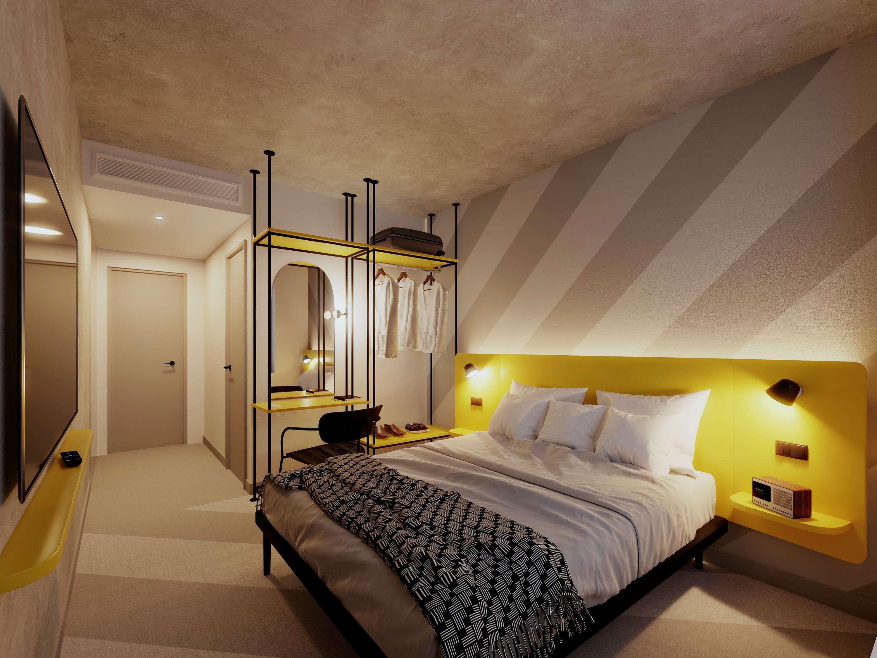 Une chambre à coucher moderne avec un lit, une coiffeuse avec un miroir et un téléviseur.