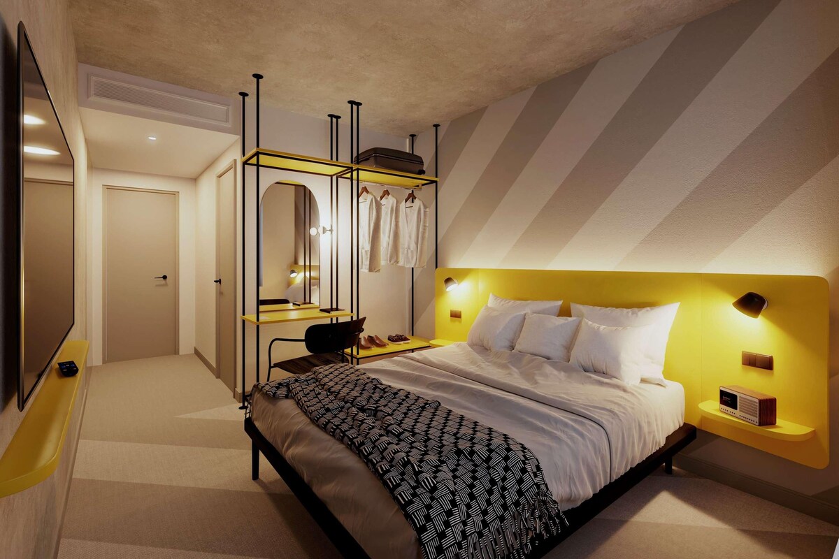 Une chambre à coucher moderne avec un lit, une coiffeuse avec un miroir et un téléviseur.