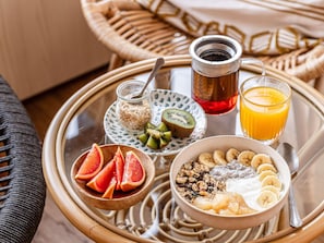 Una bandeja de desayuno con un tazón de cereal, rodajas de plátano y un vaso de jugo de naranja.