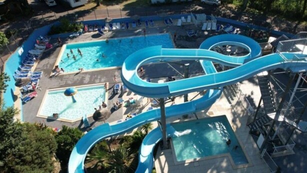 A water park with multiple pools, a large water slide, and lounge chairs.