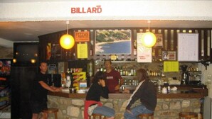 Un espace bar avec des tabourets, un comptoir et une enseigne indiquant « BILLARD  ».