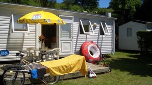 Ein Wohnmobil mit einem gelben Sonnenschirm, einem Fahrrad und einem roten Reifen.