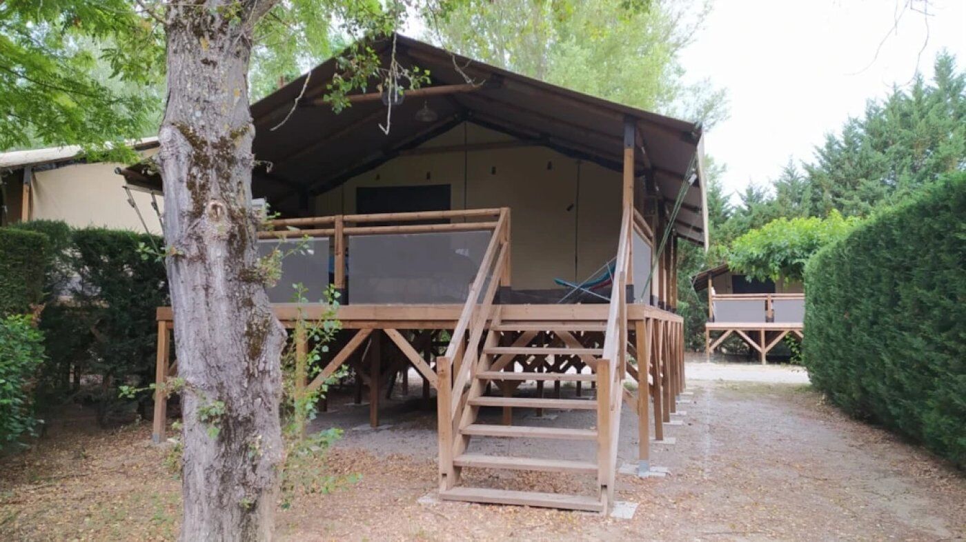 A rustic wooden cabin with a porch and a staircase leading to a deck.