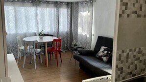 Een ruimtelijke leefruimte met een eethoek, een bank en een kitchenette.
