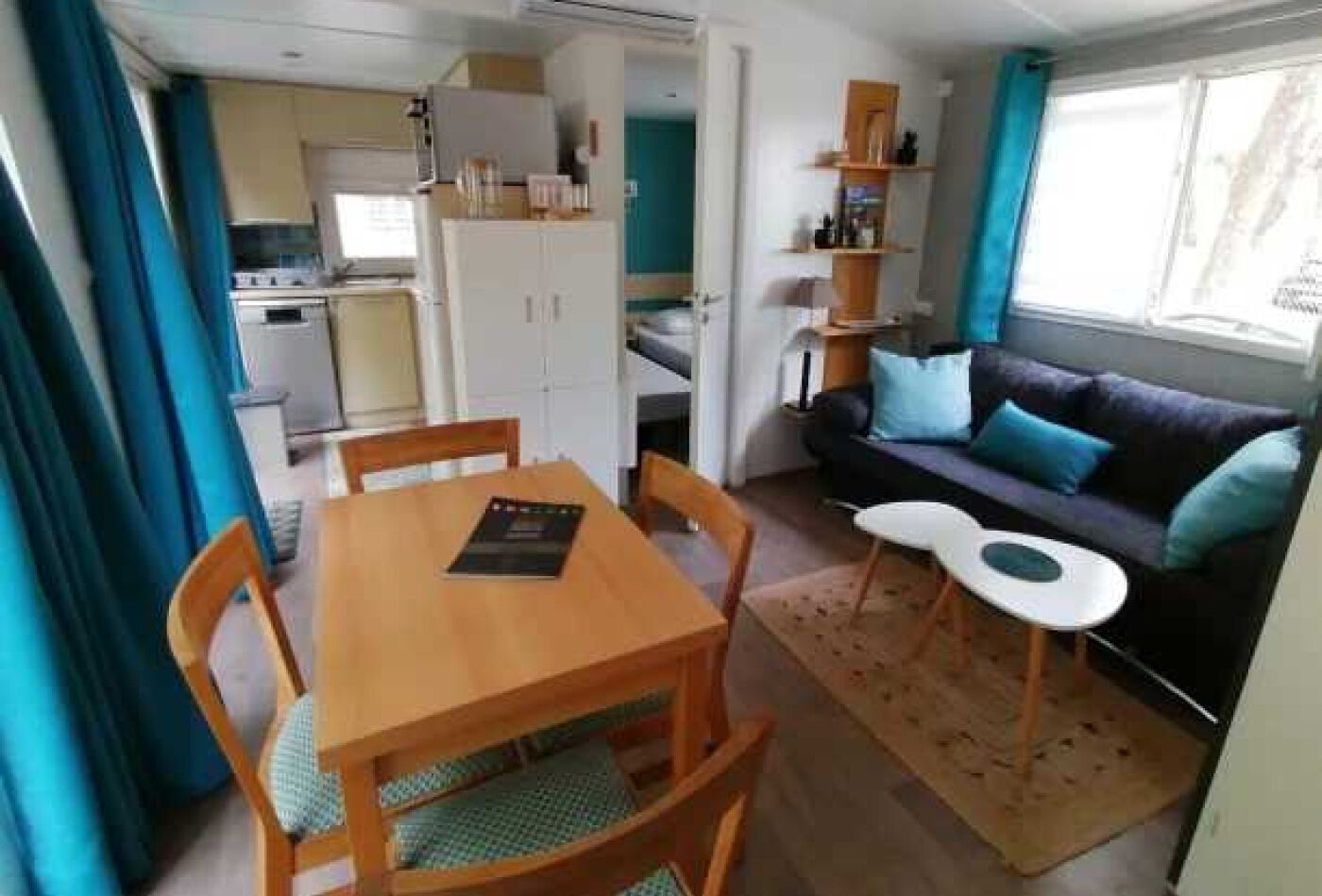 Un espace de vie compact comprenant une table à manger, des chaises, un canapé et une petite kitchenette.