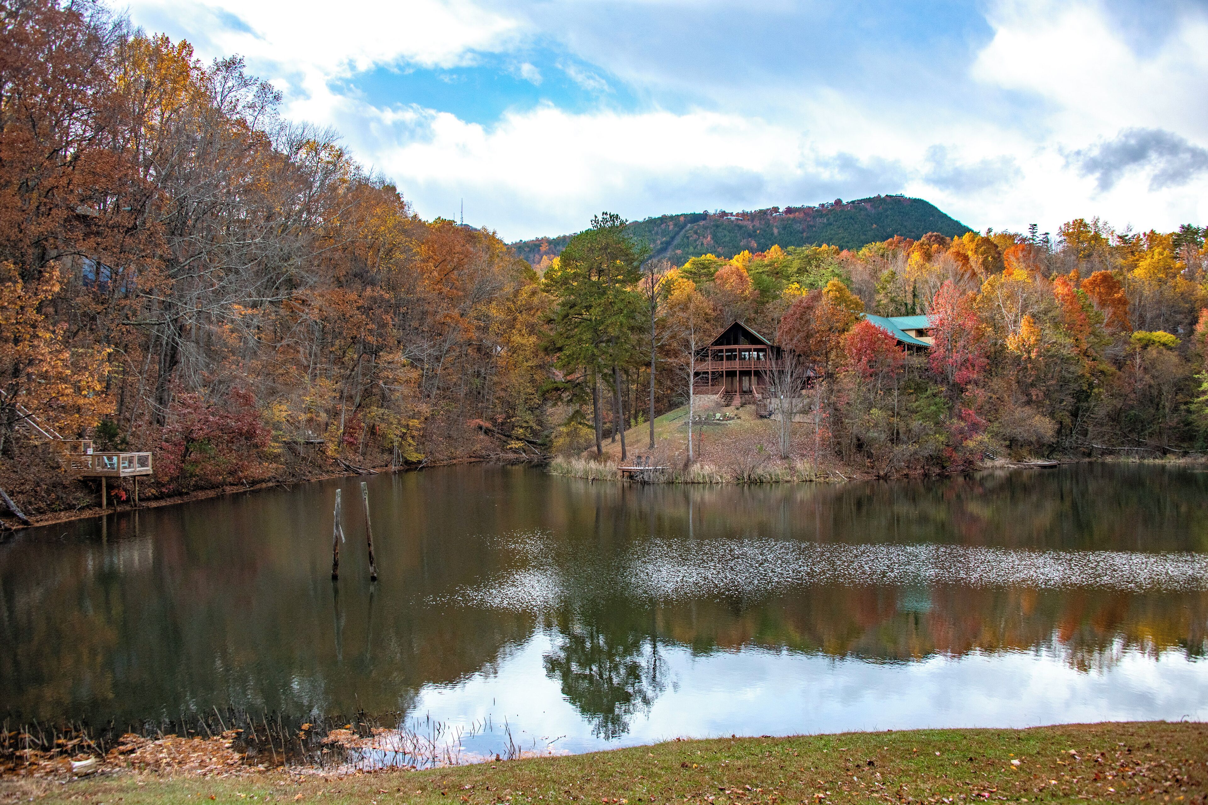 A cabin by a lake surrounded by autumn foliage.