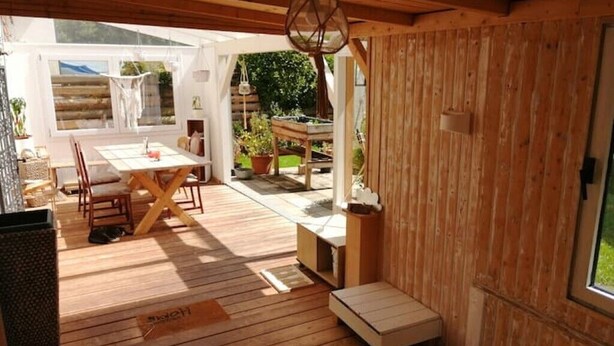 Un interior de madera con zona de comedor, una mesita y un banco.