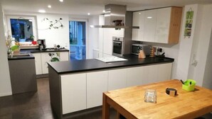 Una cocina moderna con armarios blancos, una encimera negra y una mesa de comedor de madera.