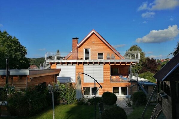 A two-story house with a wooden facade, a balcony, and a visible garage.