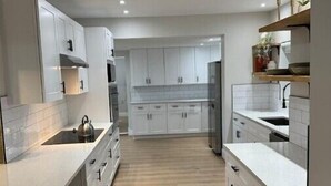 Una cocina moderna con armarios blancos, una isla central y piso de madera.