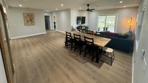 Amplia sala de estar con mesa de comedor, sillas, sofá y televisor.