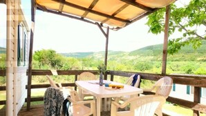 Un área de estar techada al aire libre con una mesa y sillas, con vistas a un paisaje pintoresco.
