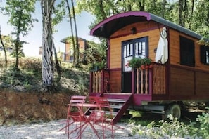 A wooden cabin with a porch, steps, and a bench.