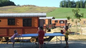 Zona de juegos infantiles con mesa de ping pong y un pequeño edificio al fondo.