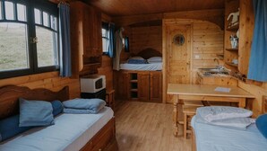 Una cabaña compacta con interior de madera, una kitchenette, una cama y una mesita.