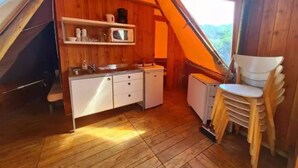 Un petit espace clos comprenant un coin cuisine, des murs en bois et une fenêtre donnant sur l’extérieur.