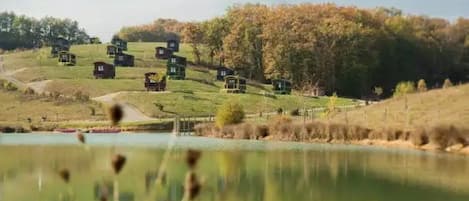A serene lakeside setting with multiple cabins, a clear sky, and autumn foliage.