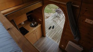 A compact kitchenette with a sink, a kettle, and a small countertop. There is a wooden deck outside with a chair and a table. - ZEcamping 4 étoiles familial piscine chauffée roulotte 9m2 2 pers (Estipouy)