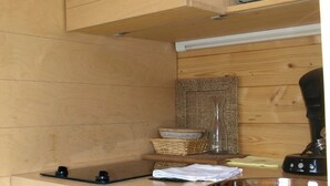 A compact kitchen with wooden cabinets, a microwave, a coffee maker, and a small sink. - ZEcamping 4 étoiles familial piscine chauffée roulotte 9m2 2 pers (Estipouy)