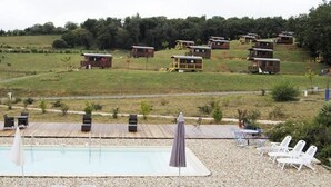 Un área de piscina con sillones de descanso y una terraza de madera.