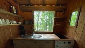 Cocina de cabaña de madera compacta, con un fregadero, un microondas y una lavadora.