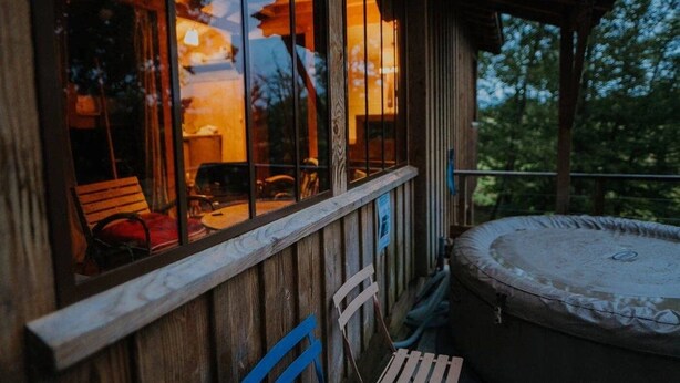 Eine Holzterrasse mit einem Whirlpool, einem Holzstuhl und einem Tisch mit Stühlen.