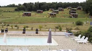 Ein Poolbereich mit Liegestühlen, einem kleinen Pool und mehreren Kabinen im Hintergrund.