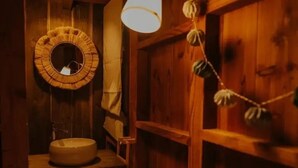 Ein Badezimmer aus Holz mit einem runden Spiegel, einem Waschbecken und einer hängenden Leuchte.