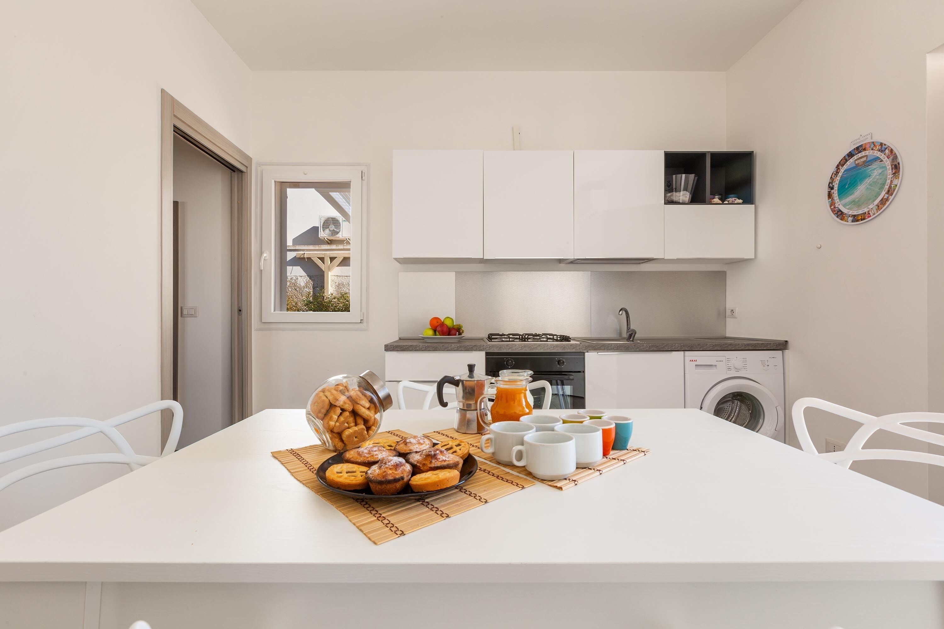 A modern kitchen with white cabinets, a dining table with a placemat, and a coffee station.