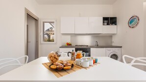 Une cuisine moderne avec des meubles blancs, une table à manger avec un set de table et un coin café.