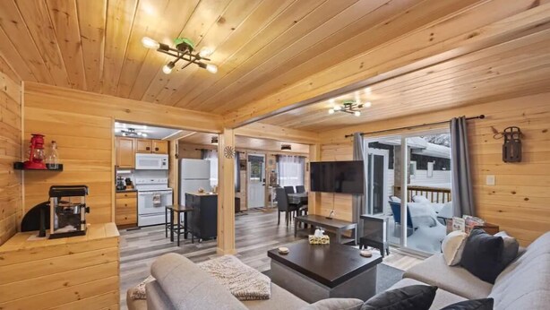 A cozy cabin interior with a living room, kitchen, and dining area.
