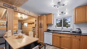 A modern kitchen with wooden cabinets, a black countertop, and a welcome sign.