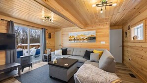 A cozy cabin interior with a large sofa, a coffee table, and a TV.
