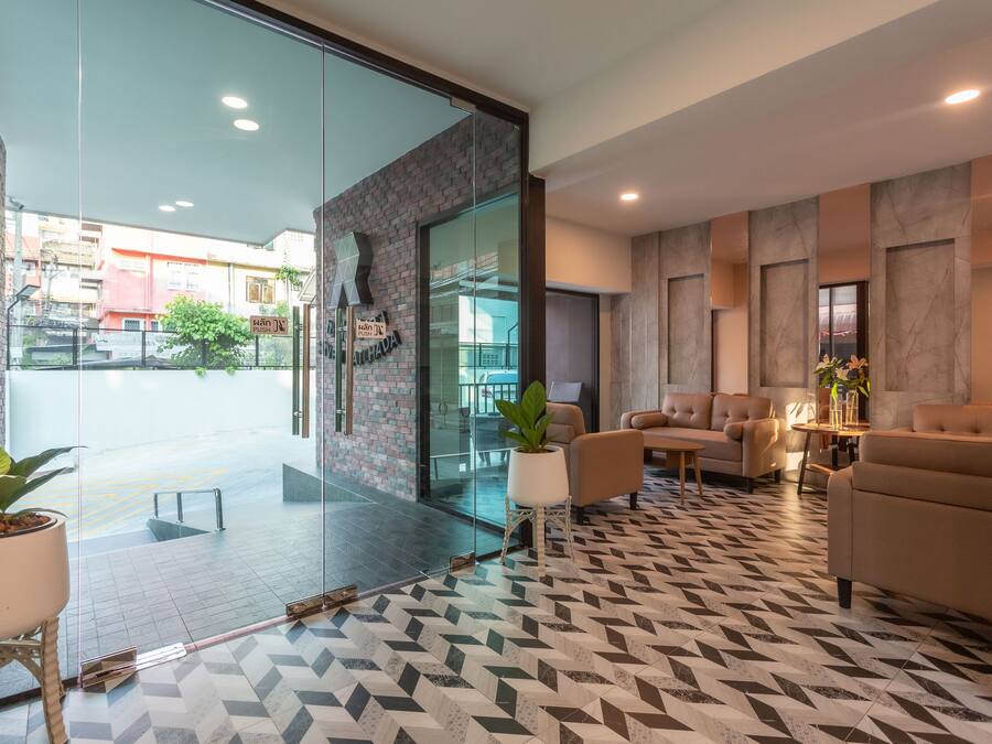 Een moderne lobby met een patroon vloer, een zithoek met banken en een glazen wand die uitkomt op een buitenruimte.