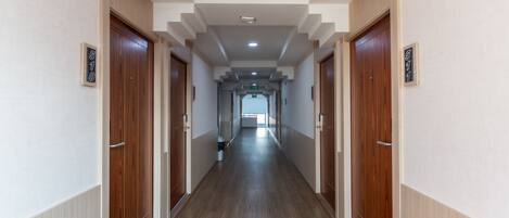 A long, narrow hallway with wooden doors on both sides, each marked with a number.