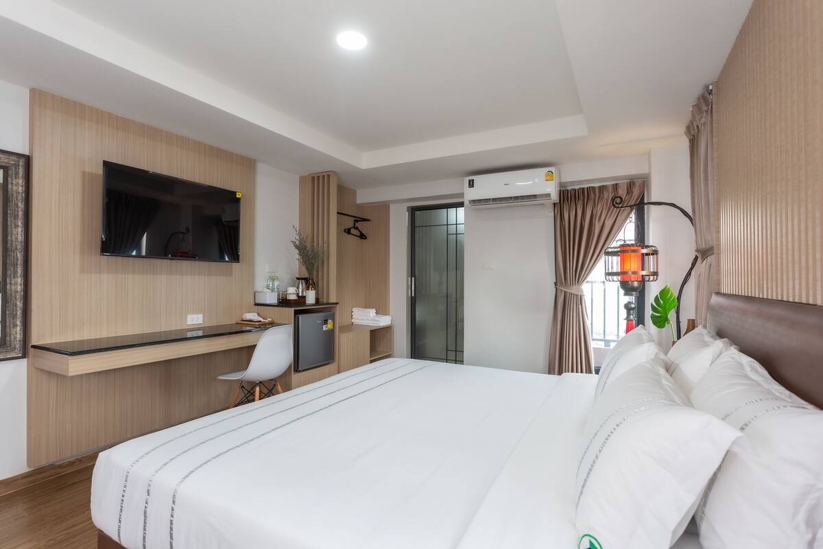 Une chambre d’hôtel moderne équipée d’un lit, d’un bureau, d’une chaise, d’une télévision et d’un appareil de climatisation.