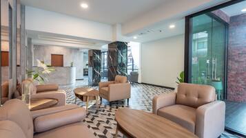A modern lobby with leather sofas, wooden tables, and a patterned floor.