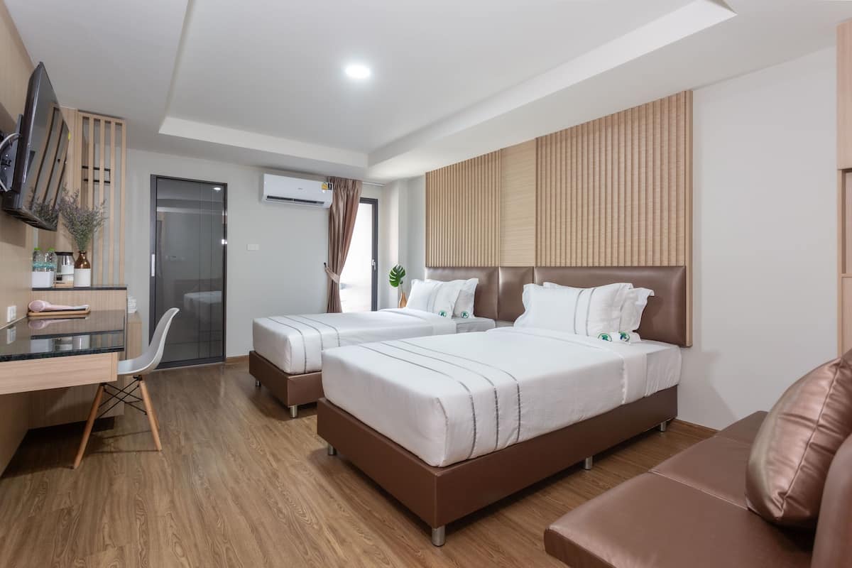 Une chambre d’hôtel moderne équipée de deux lits, d’un bureau, d’une chaise et d’un téléviseur fixé au mur.