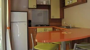 A compact kitchen with a refrigerator, stove, and a small dining table with chairs.