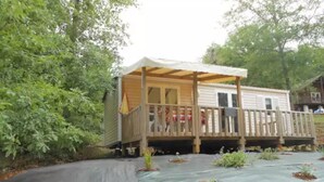 A small wooden structure with a porch, surrounded by greenery.