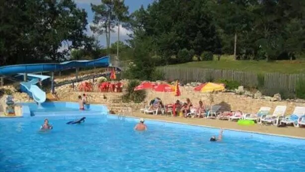 A swimming pool with a water slide, lounge chairs, and umbrellas.