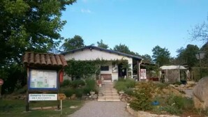 A rustic building with a gravel driveway leading to a wooden door.