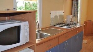 A compact kitchen with a microwave, sink, and gas stove.