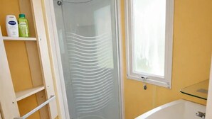 Un baño con ducha, lavamanos y ventana.
